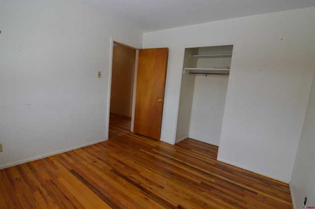 unfurnished bedroom with dark hardwood / wood-style flooring and a closet