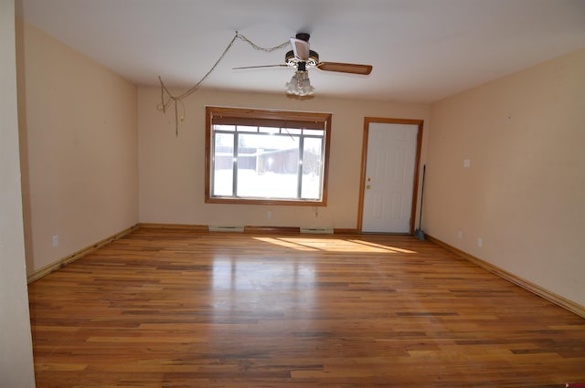 spare room featuring hardwood / wood-style flooring, ceiling fan, and a baseboard heating unit