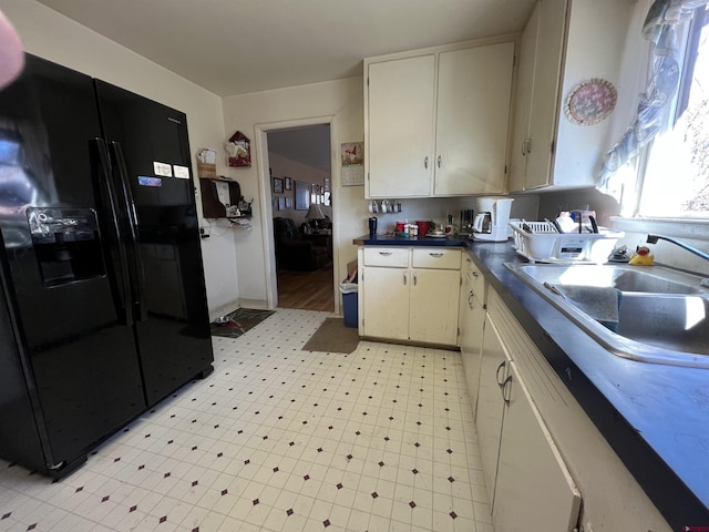 kitchen featuring white cabinetry, sink, and black refrigerator with ice dispenser