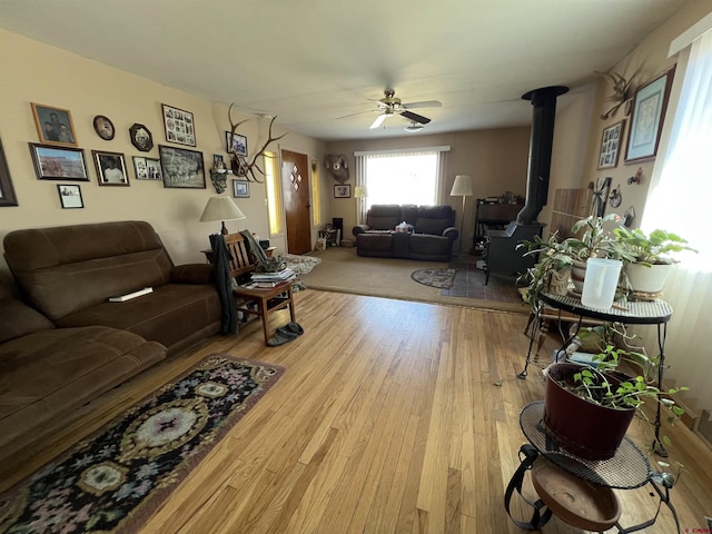 living room featuring ceiling fan, light hardwood / wood-style floors, and a wood stove