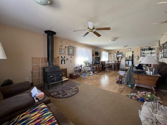 living room with hardwood / wood-style flooring, ceiling fan, and a wood stove