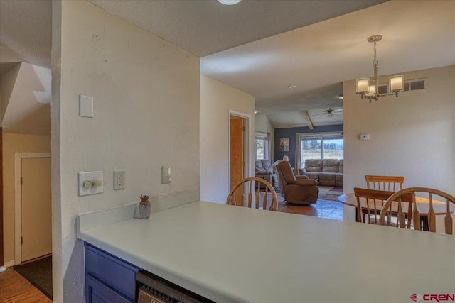 kitchen featuring lofted ceiling, hanging light fixtures, ceiling fan with notable chandelier, and wood-type flooring