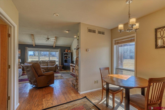 dining area with hardwood / wood-style flooring, lofted ceiling, and ceiling fan with notable chandelier