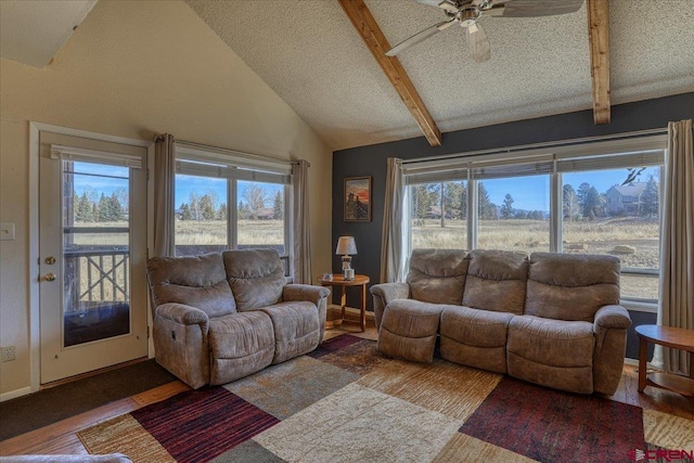 living room with ceiling fan, plenty of natural light, lofted ceiling with beams, and hardwood / wood-style floors