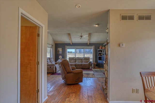 living room with vaulted ceiling with beams, a textured ceiling, wood-type flooring, and ceiling fan