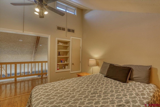 bedroom with a towering ceiling and wood-type flooring