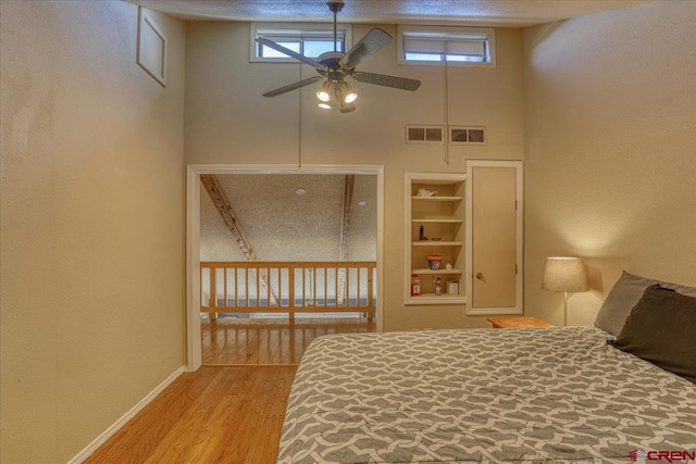 unfurnished bedroom featuring hardwood / wood-style flooring, multiple windows, and a high ceiling