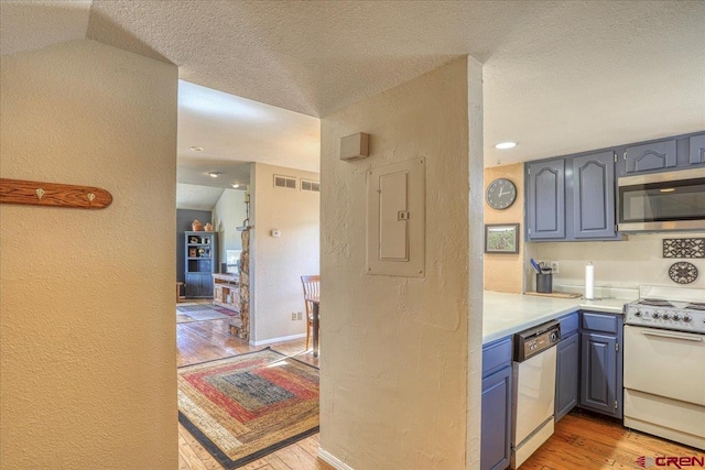 kitchen featuring lofted ceiling, light hardwood / wood-style flooring, a textured ceiling, appliances with stainless steel finishes, and electric panel