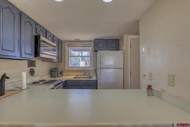 kitchen featuring white refrigerator, sink, a textured ceiling, and stove