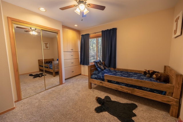 bedroom with ceiling fan, light carpet, and a closet