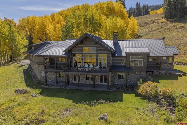 back of house featuring a deck, a lawn, and a patio area