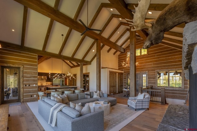 living room with light hardwood / wood-style floors, high vaulted ceiling, a notable chandelier, and beam ceiling