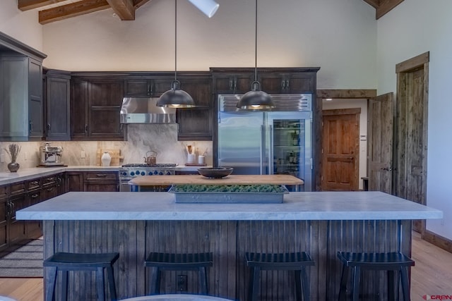 kitchen with wall chimney range hood, a center island, a kitchen breakfast bar, and high quality appliances