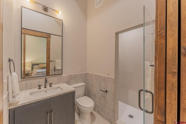 bathroom with vanity, tile walls, toilet, and a shower with door