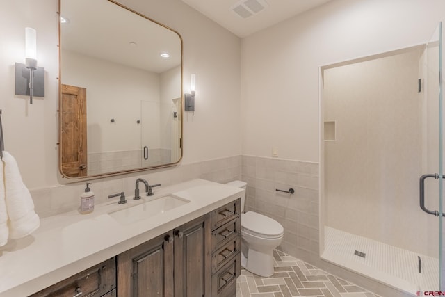 bathroom with a shower with shower door, vanity, tile walls, and toilet