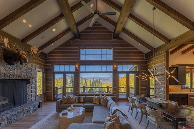 living room featuring high vaulted ceiling, beamed ceiling, a stone fireplace, and wood-type flooring