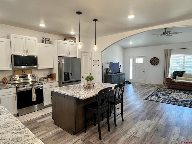 kitchen featuring appliances with stainless steel finishes, light stone countertops, a breakfast bar, and white cabinets