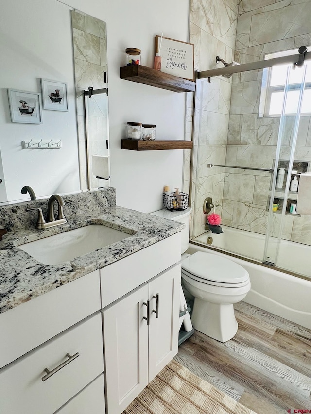 full bathroom featuring hardwood / wood-style flooring, enclosed tub / shower combo, vanity, and toilet