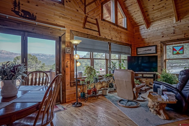 dining space featuring beam ceiling, wooden walls, plenty of natural light, and wood ceiling