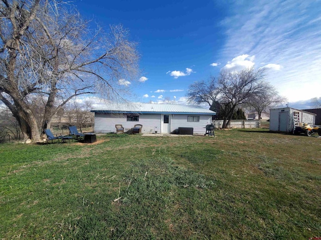 rear view of house with a storage shed, a yard, metal roof, and an outdoor structure