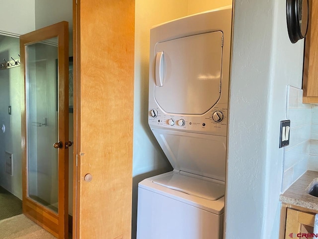 laundry room featuring stacked washer / drying machine