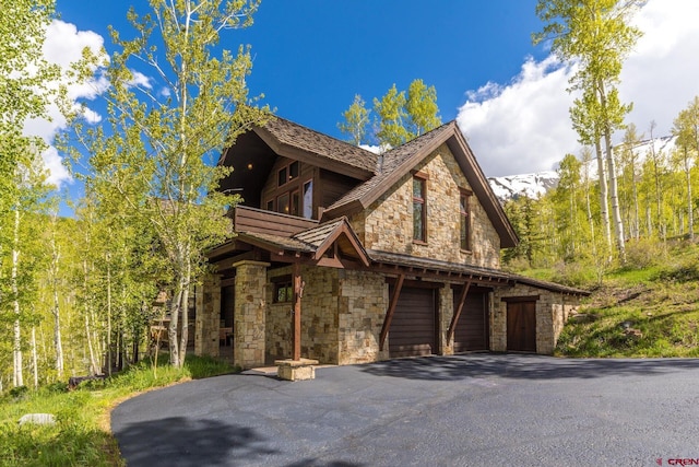 view of front of house featuring stone siding, aphalt driveway, and an attached garage