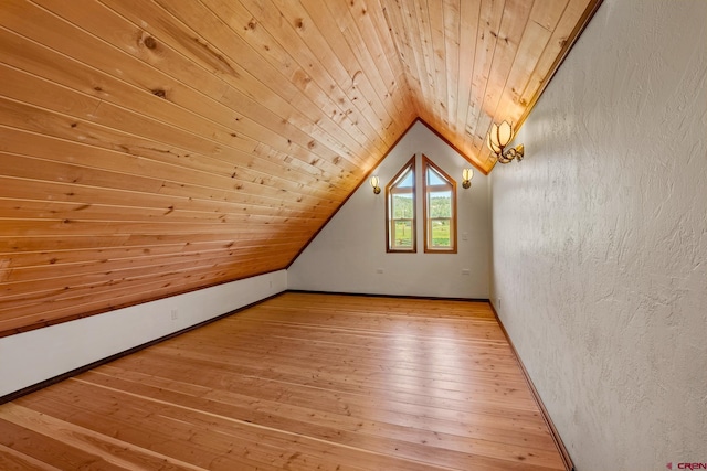 additional living space featuring lofted ceiling, a textured wall, wood ceiling, wood finished floors, and baseboards