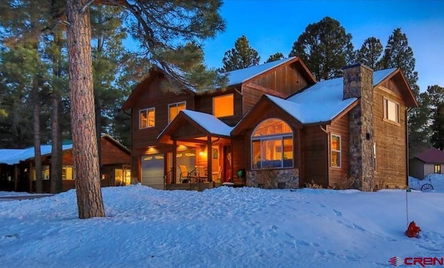 rustic home with a garage, covered porch, and a chimney