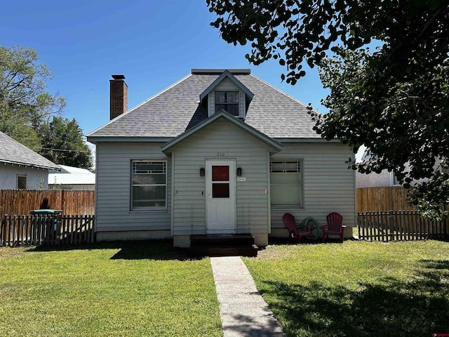 bungalow-style home featuring a shingled roof, fence, and a front yard