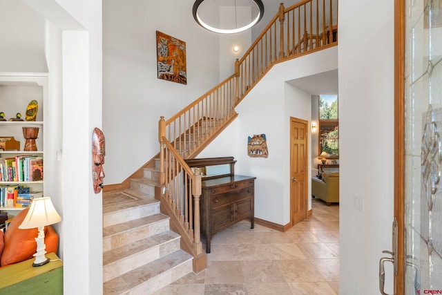 stairs featuring a high ceiling and baseboards