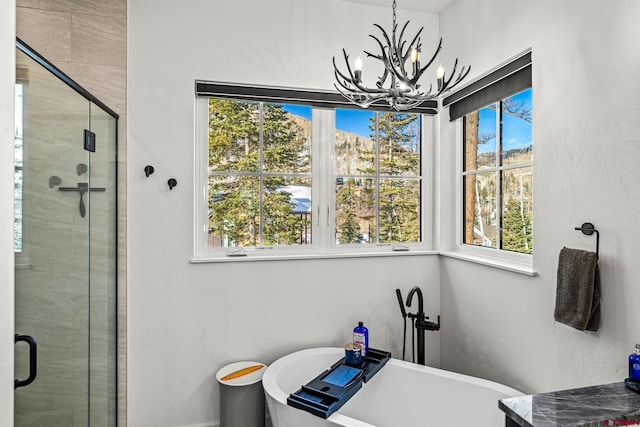 bathroom featuring a freestanding bath, a notable chandelier, a shower stall, and a healthy amount of sunlight