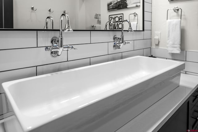 bathroom featuring a freestanding tub, a sink, and tile walls