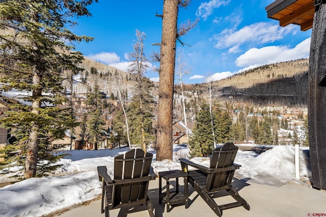 snow covered patio with a mountain view and fence