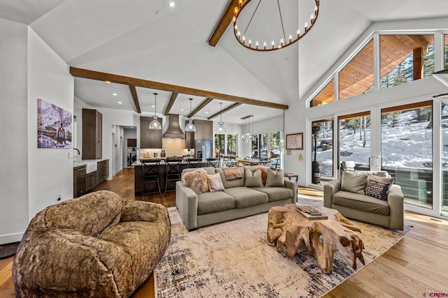 living room with high vaulted ceiling, beamed ceiling, wood finished floors, and an inviting chandelier