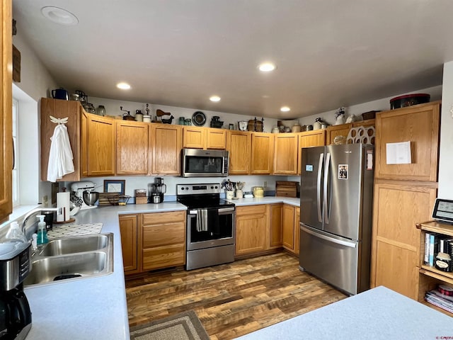 kitchen with recessed lighting, stainless steel appliances, dark wood-type flooring, a sink, and light countertops