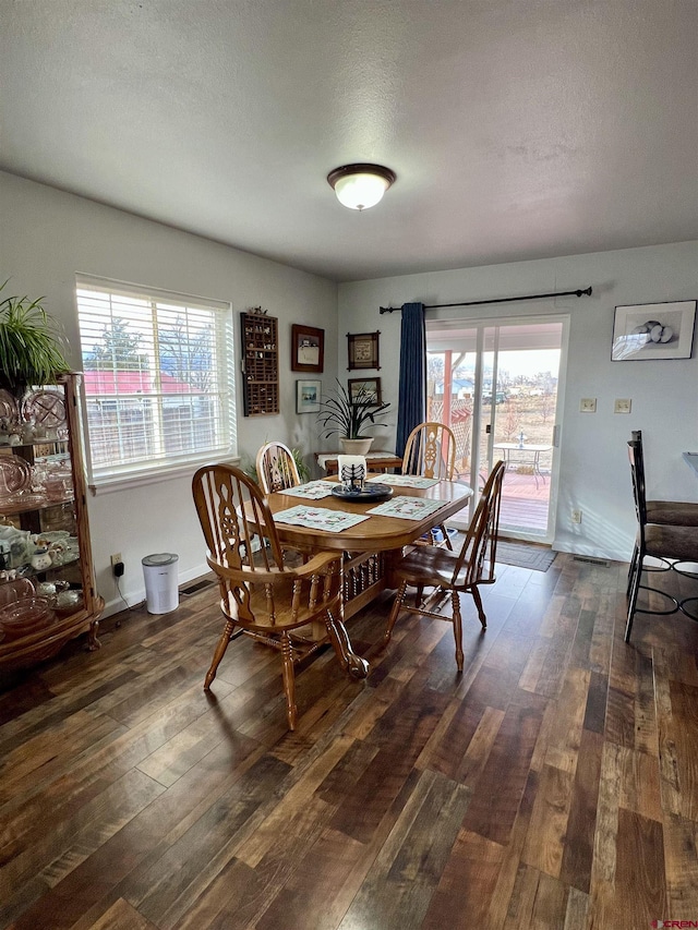 dining area with a textured ceiling, baseboards, and dark wood-type flooring