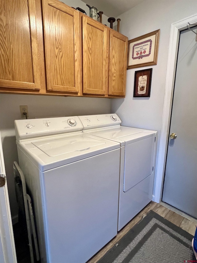 washroom featuring cabinet space, separate washer and dryer, and wood finished floors