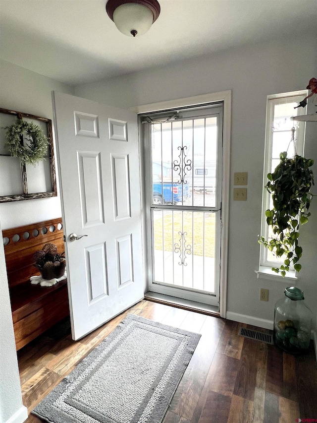 doorway to outside with visible vents, baseboards, and wood finished floors