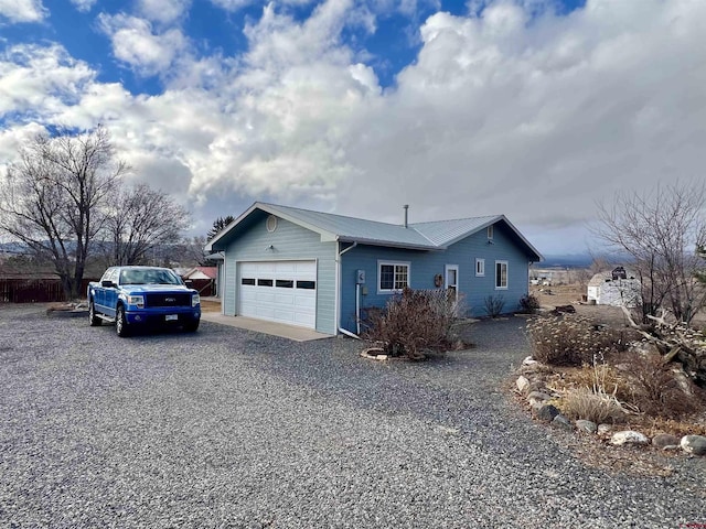 exterior space with a garage, driveway, and metal roof