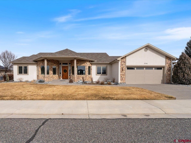 view of front of house with a garage, stone siding, driveway, stucco siding, and a front yard