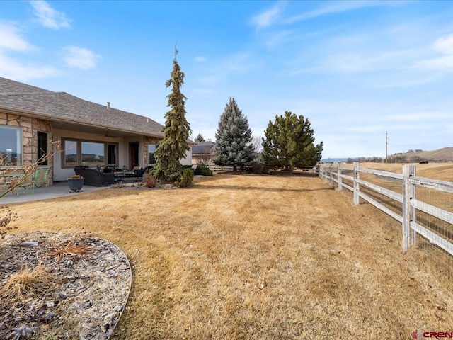 view of yard with a rural view, fence, and a patio