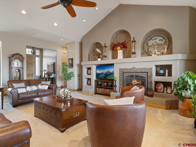 living area with built in features, recessed lighting, light carpet, ceiling fan, and a warm lit fireplace