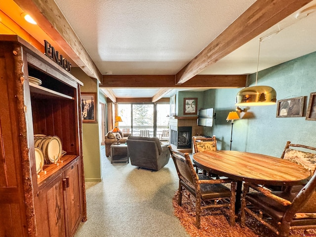 carpeted dining space with a textured ceiling, a fireplace, and beamed ceiling