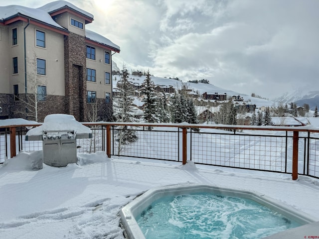 snow covered pool with fence, area for grilling, and a mountain view