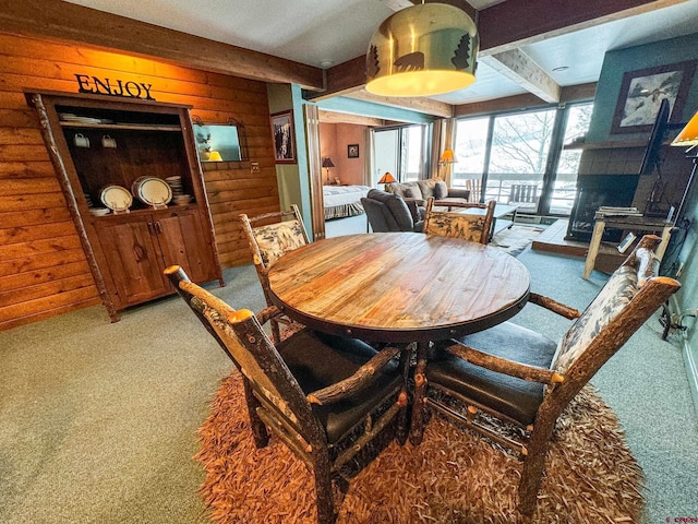 dining space featuring beam ceiling, carpet flooring, wood walls, and a fireplace