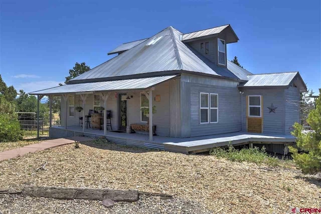 view of side of home with covered porch and metal roof