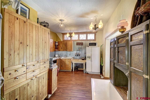 kitchen featuring a chandelier, white appliances, dark wood-style flooring, light countertops, and decorative light fixtures