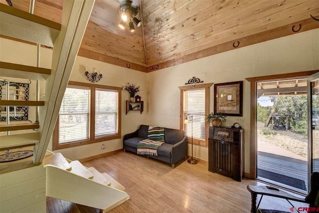 living area with high vaulted ceiling, light wood-type flooring, baseboards, and a ceiling fan