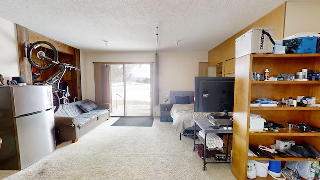 interior space with light carpet, a textured ceiling, freestanding refrigerator, and access to exterior