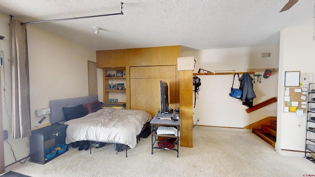 bedroom with light colored carpet and a textured ceiling